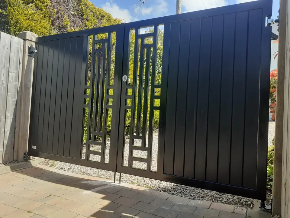 Black metal driveway gates with a lattice pattern